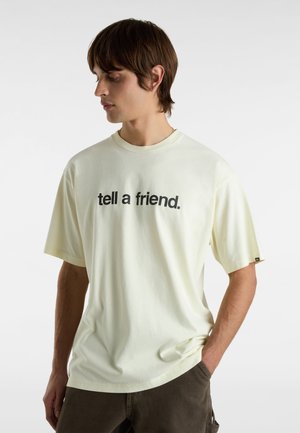 Helles gelbes Baumwoll-T-Shirt mit kurzen Ärmeln, auf der Vorderseite mit dem Text "sag es einem Freund." in fetten schwarzen Buchstaben bedruckt.