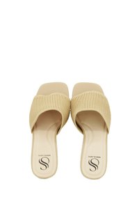 Sandali scivolati beige con una banda a coste testurizzata e una soletta liscia, dotati di suola piatta e design minimalista.