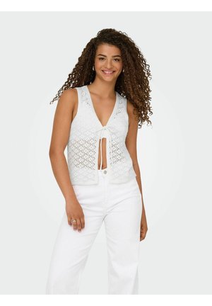 Witte haak tanktop met een V-hals en strikdetail, met een ruitpatroon en open brei-details, gecombineerd met hoge witte broek.