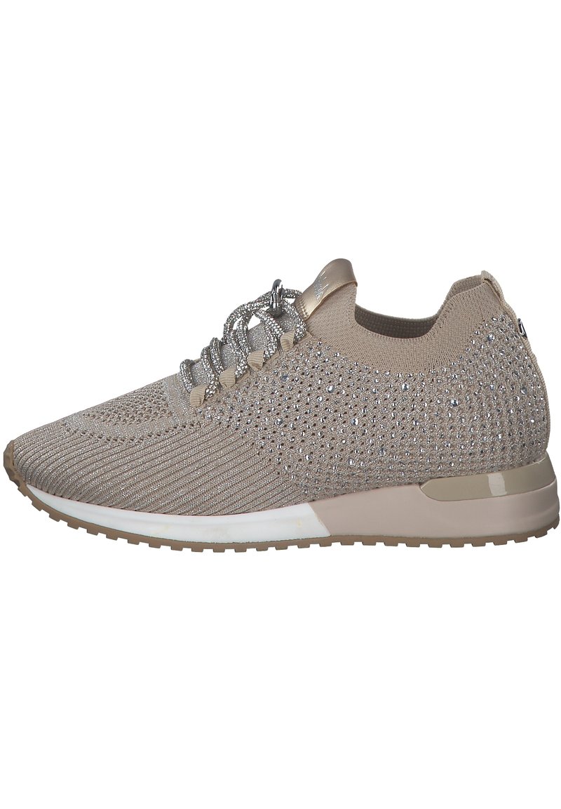 Chaussure de sport beige avec une tige en tricot texturé, rehaussée d'embellissements argentés et de lacets réfléchissants ; semelle extérieure légère avec un contour blanc.