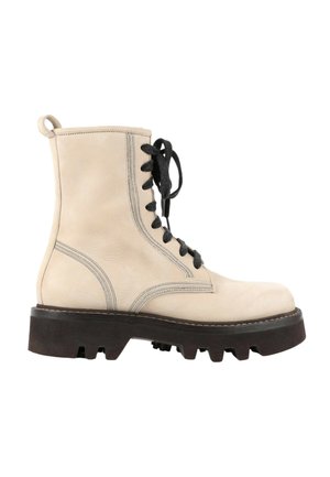 Bottine beige en cuir à lacets avec semelle épaisse noire à crampons et lacets noirs, dotée de coutures renforcées et d'une languette à l'arrière.
