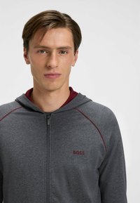 Gray zip-up hoodie with a maroon interior lining, featuring a contrasting maroon stitch, and a small red "BOSS" logo on the chest.