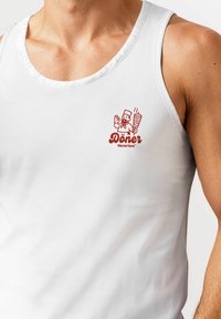 White sleeveless tank top featuring a red graphic logo with a cartoon chef and the text "Döner Neverless." Smooth texture, standard fit.
