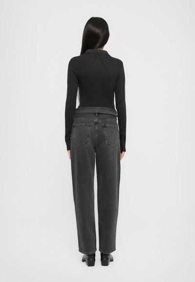 Black long-sleeve top with a collared neck, paired with loose-fit gray denim jeans featuring back pockets and a frayed hem.