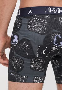 Fekete boxer alsónadrág mintás kialakítással, szürke és fehér motívumokkal, elasztikus anyagból készült, sötétkék derékrésszel, amelyen a Jordan logó látható.