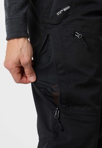 Black pants with a zippered pocket and mesh lining, featuring an adjustable waistband and durable fabric for flexibility and breathability.