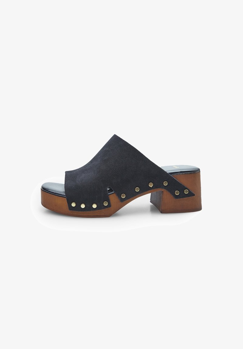 Černé semišové sandály s otevřenou špičkou a širokým páskem, zdobené mosaznými hřebíky a dřevěným blokovým podpatkem. Hladká černá stélka doplňuje celkový design.