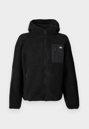 Veste en polaire noire avec une capuche, des fermetures zippées et une poche sur la poitrine. Elle présente un matériau texturé et confortable ainsi que des panneaux noirs unis.