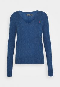 Blue cable-knit sweater with a V-neck, long sleeves, ribbed hem, and a small red logo on the chest. Made from a soft, textured material.