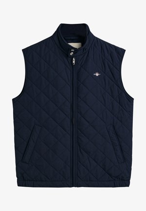 Gilet matelassé bleu marine avec un col haut, fermeture éclair sur le devant et deux poches latérales, arbore un logo sur la poitrine.