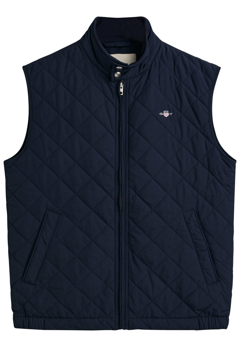Gilet matelassé bleu marine avec un col haut, fermeture éclair sur le devant et deux poches latérales, arbore un logo sur la poitrine.
