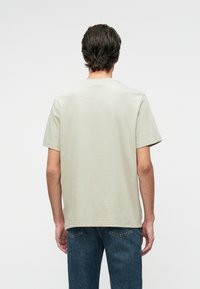 Light grey short-sleeve t-shirt with a plain texture, relaxed fit, and a crew neckline, paired with blue denim jeans.