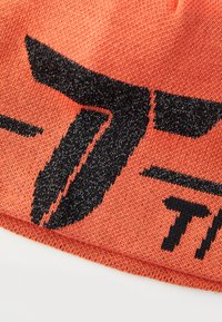 Berretto a maglia di un vivace arancione con una grafica nera che presenta un logo stilizzato. Il materiale sembra morbido ed elastico, adatto per il freddo.