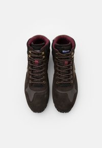 Brązowe zamszowe buty sportowe za kostkę z teksturowanym czarnym meshowym językiem, bordowymi akcentami, brązowymi sznurowadłami oraz gumową podeszwą z wytrzymałym bieżnikiem.