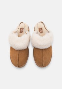 Pantoufles en daim brun avec doublure en fourrure blanche et design à tige fendue. Comprend un accent de marque le long du bord du talon.