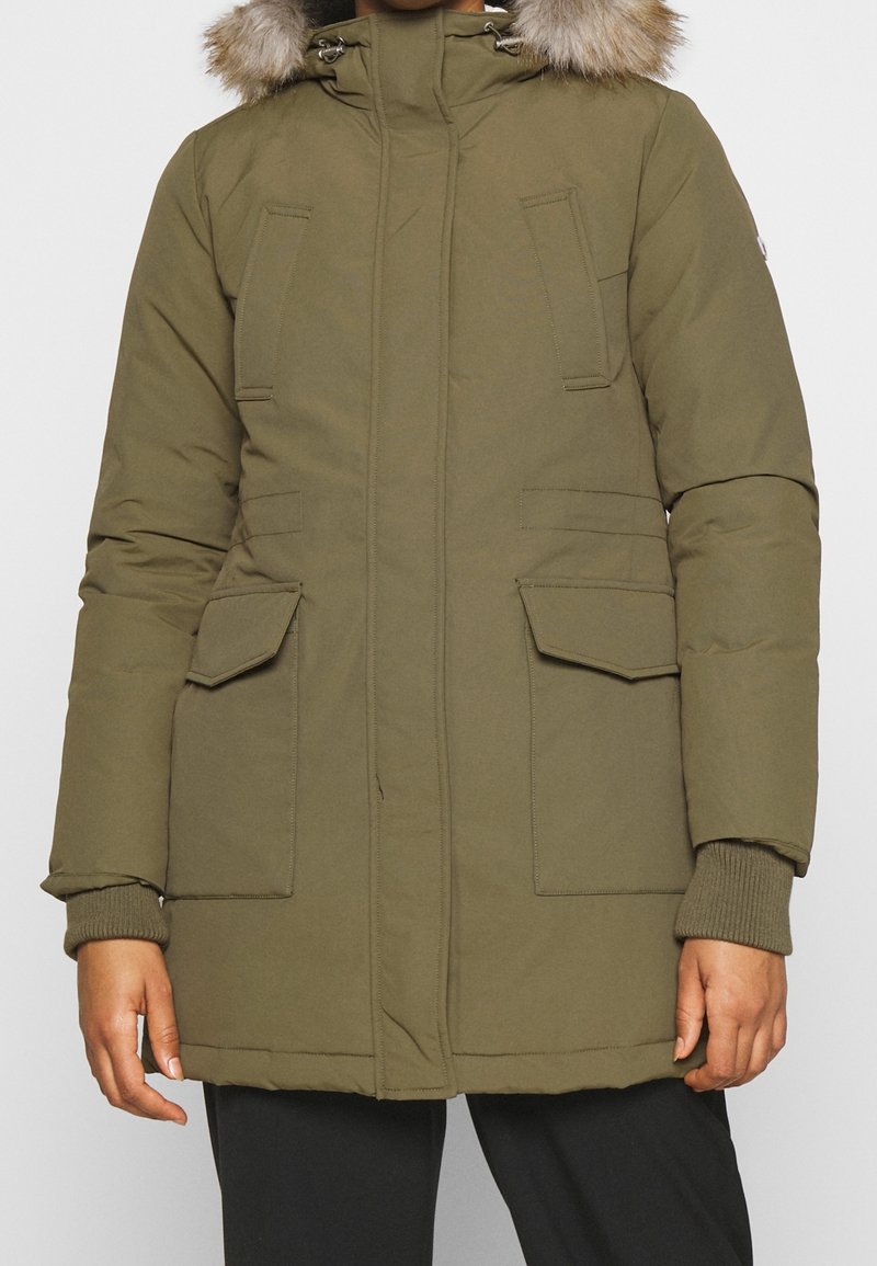 Olivgrön parka med en mjuk pälsluva, framdragkedja och tryckknappar, två stora sidofickor och ribbade muddar för värme.