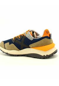 Zapatillas deportivas con un cuerpo de malla azul marino, acentos de ante beige, cordones naranjas y una suela acolchada con un patrón texturizado y elementos de diseño en negro.