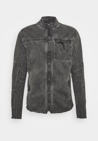 Mörkgrå tvättad jeansjacka med ståkrage, framsida med dragkedja och ficka med dragkedja på bröstet, har stickade paneldetaljer på ärmarna.