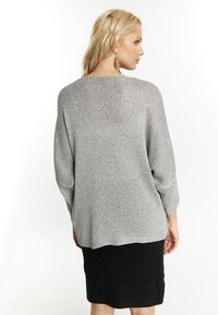 Maglione argento con vestibilità ampia, lavorazione a maglia testurizzata e maniche a tre quarti, abbinato a una gonna nera aderente.