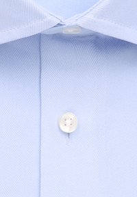 Tessuto di camicia leggermente azzurro con una trama testurizzata, caratterizzato da un bottone in plastica nel colletto e una piastra cucita.