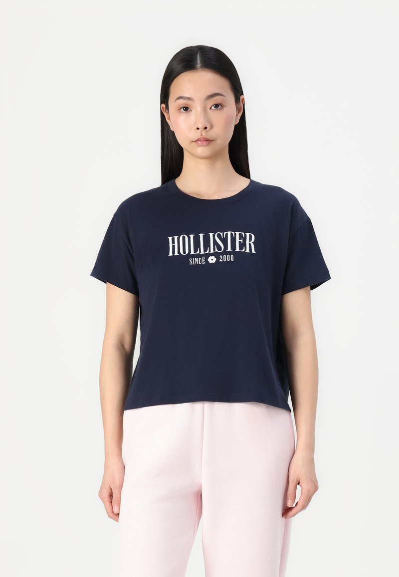 Námornícky modré bavlnené tričko s krátkymi rukávmi a okrúhlym výstrihom, na prednej strane s bielym potlačou "HOLLISTER SINCE 2000".