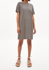 Sukienka w paseczki w czarno-białym kolorze z bawełny, krótki rękawek, luźny fason, do kolan. W komplecie z beżowymi sandałami na paski.