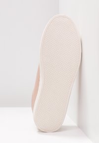 Light pink sneaker with a textured suede upper, featuring a white rubber sole and diamond-patterned tread for grip.