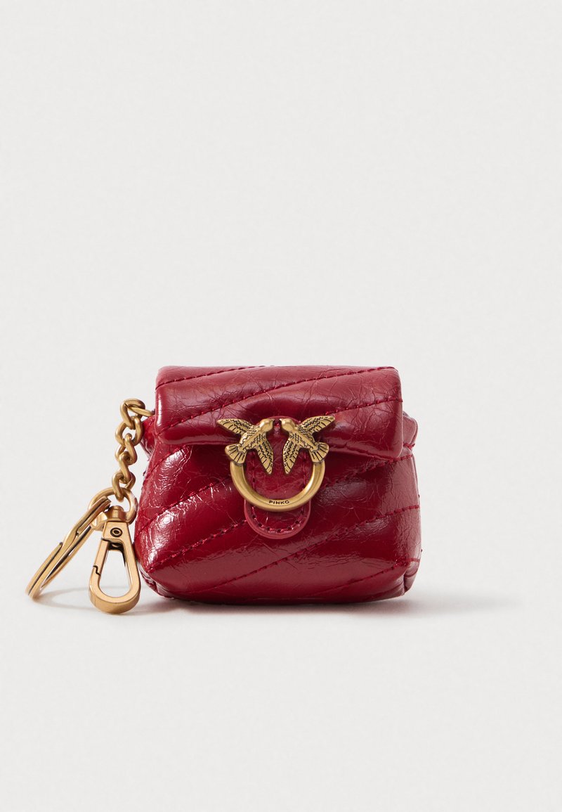 Mini bolsa vermelha em couro matelassê com ferragens douradas, apresenta uma fivela com motivo de pássaro e alça de corrente destacável. Forma compacta e arredondada.