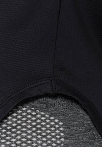 Tela negra texturizada con un patrón de cuadrícula, con un dobladillo curvado. El material subyacente es de un gris más claro con un diseño de puntos.