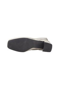 Zapato gris con parte superior lisa, suela de goma negra gruesa y tacón rectangular. Detalle de la plantilla texturizada visible. Diseño minimalista.