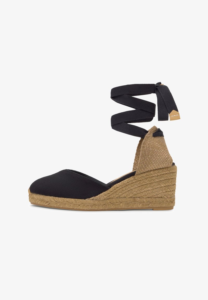 Espadrille compensée en toile noire avec semelle plateforme en jute tressé et long ruban noir à nouer autour de la cheville.