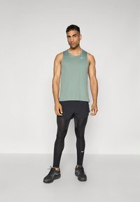 Roheline varrukateta sporditopp väikese logoga, mustad lühikesed püksid, mustad pikkade pükstega sukad ja mustad tossud. Sile kangas, istuv lõige.