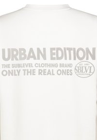 Weißes Sweatshirt mit grauem Text, der "URBAN EDITION" und "DIE SUBLEVEL CLOTHING MARKE NUR FÜR DIE ECHTEN" liest, mit einem runden Logo.