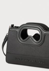 Borsa in pelle nera con texture, dotata di manico integrato a intaglio e logo "KARL LAGERFELD" impresso sul pannello frontale inferiore.