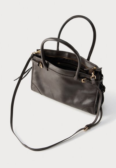 Sac à main en cuir marron foncé avec deux poignées, une longue bandoulière réglable et des détails de fermeture éclair dorés, présenté sur un fond blanc.