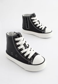 Sorte høje sneakers lavet af læder med hvide syninger, gummitåhætte og hvide snørebånd; har en sideside lynlås og snørehuller.