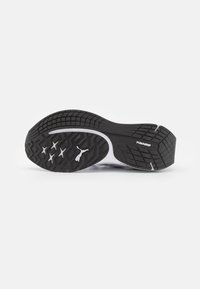 Black rubber shoe sole with a textured pattern, featuring a white accent and Puma logo. The design includes hexagonal treads for grip.