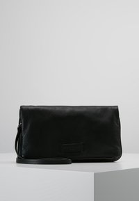 Černá kožená kabelka na zápěstí s texturovaným povrchem, klopovým uzávěrem a nastavitelným popruhem. Obsahuje nášivku s logem a kontrastní švy.