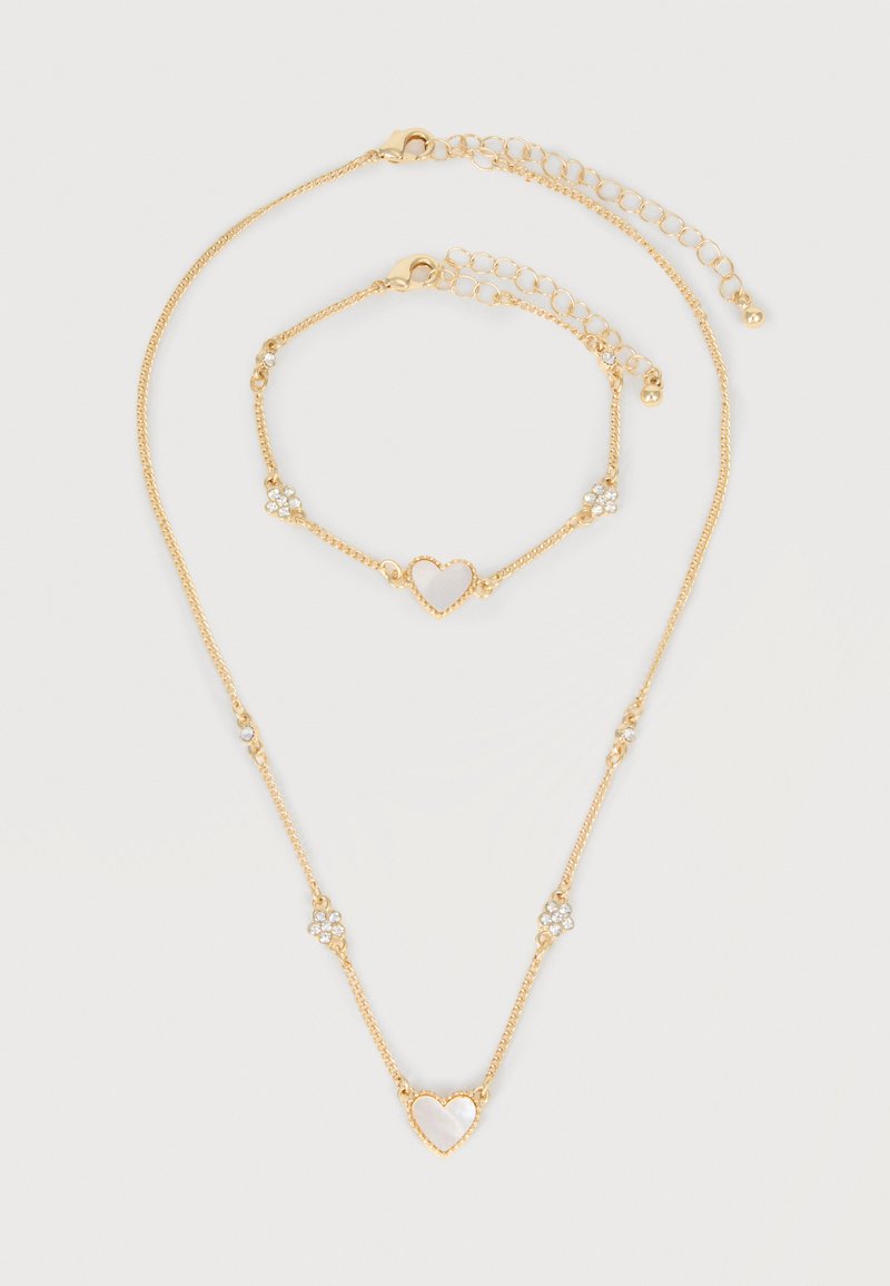 Σετ κολιέ και βραχιόλι σε χρυσό τόνο με μοτίφ από μαργαριτάρι σε σχήμα καρδιάς και μικρές συγκεντρώσεις κρυστάλλων, και τα δύο με ρυθμιζόμενο κούμπωμα αλυσίδας.