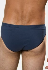 Navy siniset uimapäivävaatteet, jotka on valmistettu joustavasta kankaasta. Ne ovat sileäpintaiset ja matalavyötäröiset, ilman näkyviä kuvioita tai tarvikkeita.