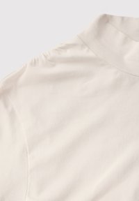 Krämfärgad kortärmad skjorta i lätt bomull, med en slät yta och en något avslappnad passform med subtila rynkor vid axlarna.