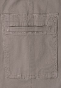 Beige Stofftasche mit horizontalem Schlitz und sichtbaren Nähten, die leichte Falten und Stoffstruktur zeigt.