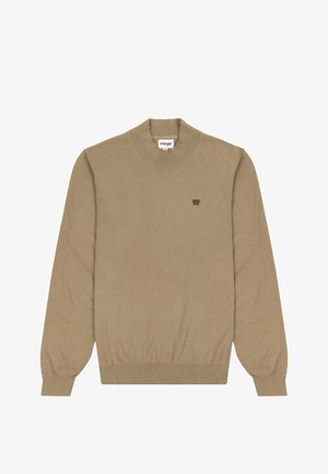 Beżowy dziany sweter z żeberkowym dekoltem i mankietami. Posiada mały brązowy emblemat logo na lewej piersi. Miękka faktura i klasyczny krój.