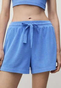 Ljust blå terrykloth-shorts med elastisk midjeband, justerbar dragsko och lös passform, med en mjuk textur och minimal detaljering.