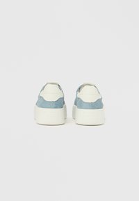 Modre semiš superge z belimi usnjenimi poudarki, debelimi belimi podplati in valovitimi detajli na peti. Čist, minimalističen dizajn.