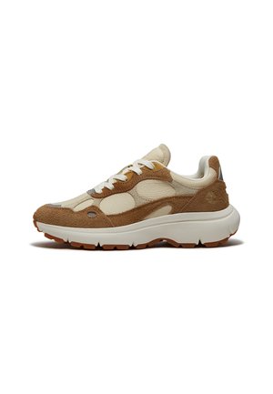 Beige und brauner Sneaker aus Velours- und Glattleder mit weißen Schnürsenkeln, dicker weißer Sohle und braunem Gummiprofil, seitlich betrachtet.