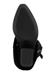 Sort ankelstøvle med en struktureret gummisål, spids tå og gulddetalje i form af lynlås. Blødt stofoverdel med en elegant silhuet.