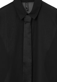 Camicia nera con colletto classico e cravatta nera unita. Realizzata in materiale trasparente con una consistenza liscia. Presenta un'etichetta che riporta la scritta "CALLIOPE."