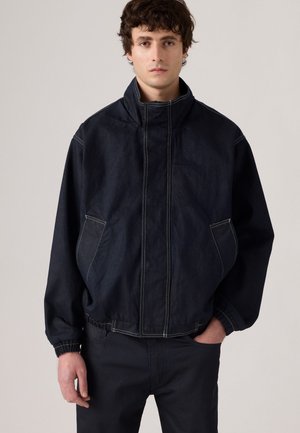 Giubbotto in denim scuro con colletto alto, polsini elastici e due tasche laterali. Presenta cuciture a contrasto e un design dal taglio comodo.