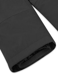 Nahaufnahme eines schwarzen, wasserdichten Hosenbeins mit elastischem Innensteg und rutschfester Griffleiste im Inneren des Saums.